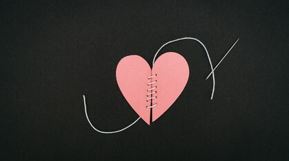 A paper heart has been cut and sown back together with thread - the needle is still visible on the left.