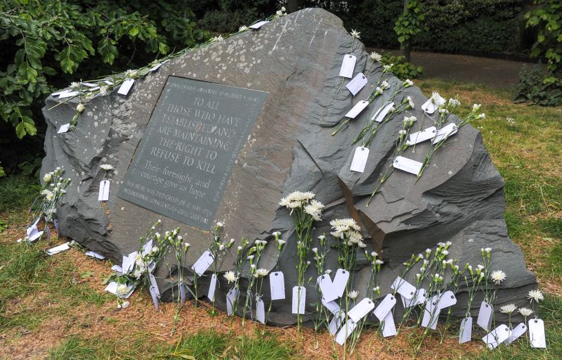 Stone with white flowers laid against it