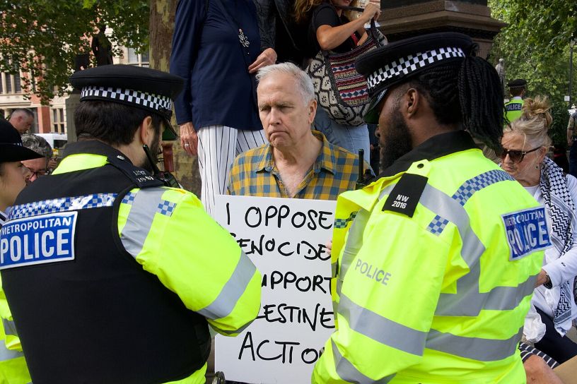 Man holding placard behind two police officers