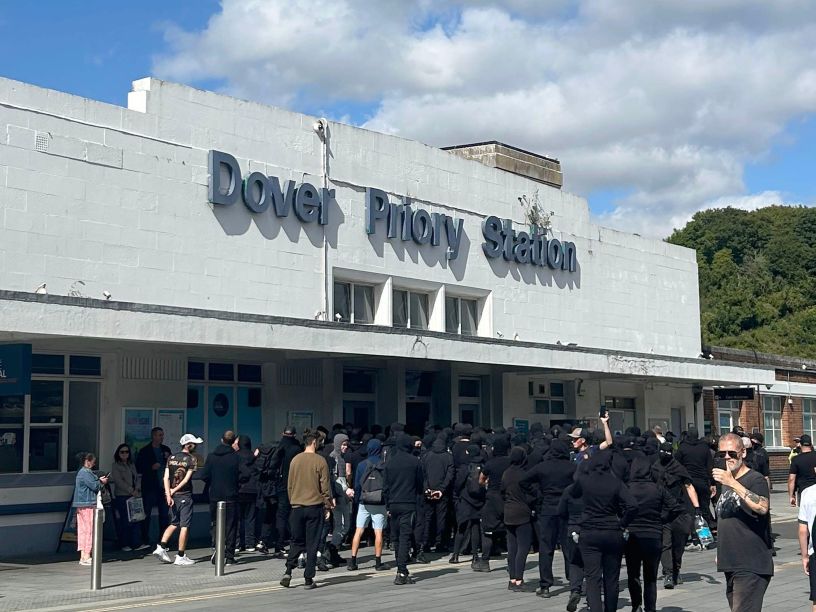 Black clad figures outside railway station