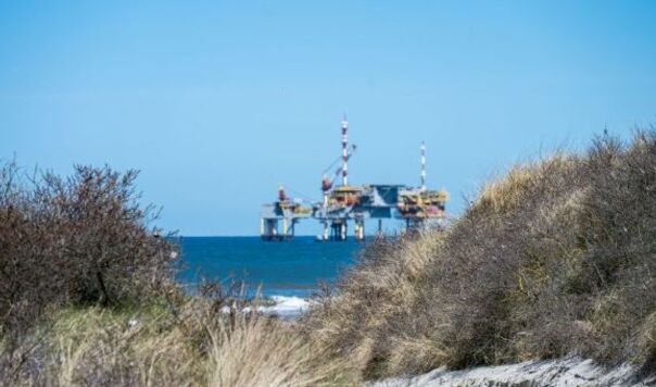Oil rig with beach and scrub in foreground